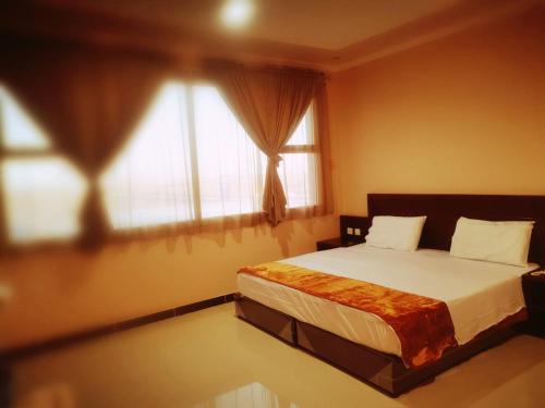 a bedroom with a bed and a large window at Sanabel Al Mish'an Furnished Units in Al Jithāmīyah