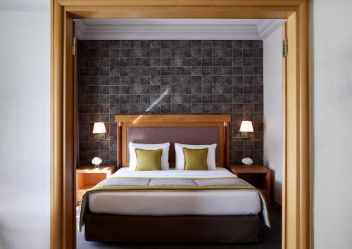 a bedroom with a large bed and a brick wall at Athens Zafolia Hotel in Athens