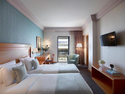 a hotel room with two beds and a desk and a television at Athens Zafolia Hotel in Athens