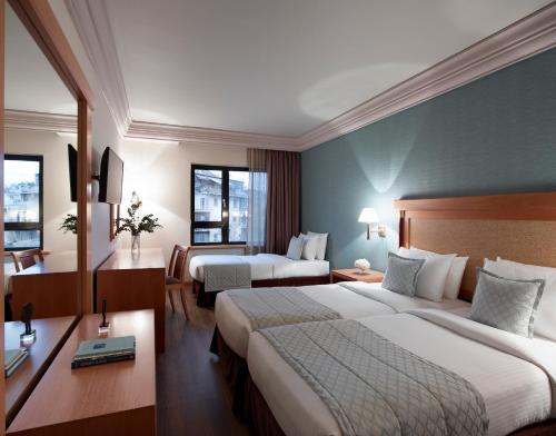 a hotel room with two beds and a desk at Athens Zafolia Hotel in Athens