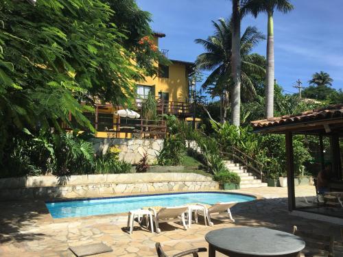 a swimming pool with chairs and tables and a house at Pousada Saint Germain in Búzios