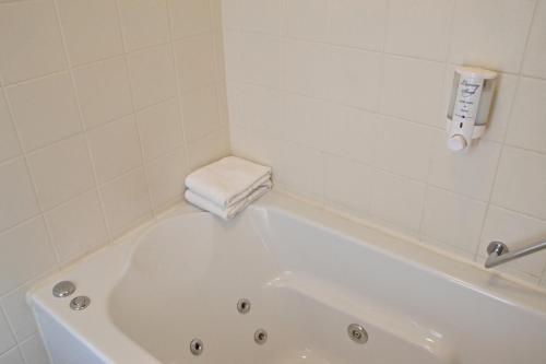 a white bath tub in a white tiled bathroom at Fletcher Hotel Restaurant Koogerend in Den Burg