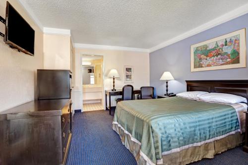 a hotel room with a bed and a desk at Travelodge by Wyndham North Richland Hills/Dallas/Ft Worth in North Richland Hills