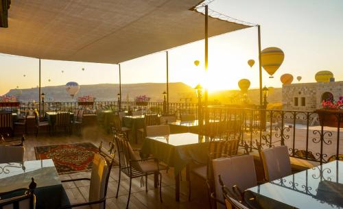 a restaurant with tables and chairs and balloons in the sky at Milat Cave Hotel in Goreme