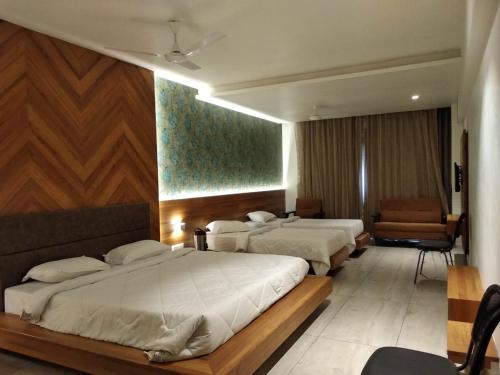 een hotelkamer met 3 bedden en een stoel bij The Bliss Hotel in Somnath