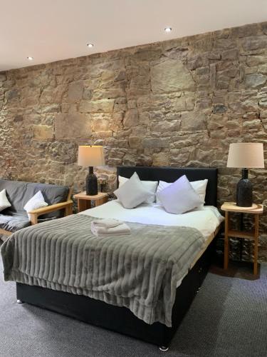 a bedroom with a bed and a stone wall at Royal Mile Suites by the Castle in Edinburgh