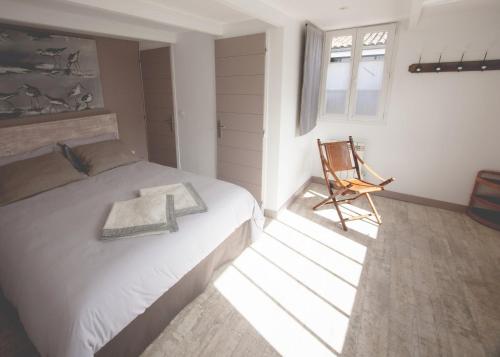 - une chambre avec un lit et une chaise dans l'établissement Maison d’hôtes Les Ajoncs, à Sainte-Marie de Ré