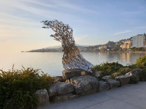 a sculpture of a tree next to a body of water at Montreux Grand Rue - Swiss Hotel Apartments in Montreux