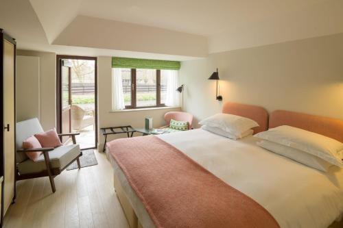 a bedroom with a bed, chair and a window at Minster Mill Hotel & Spa in Minster Lovell