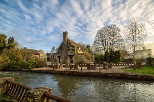 a building next to a river with a bridge at Old Swan & Minster Mill in Minster Lovell