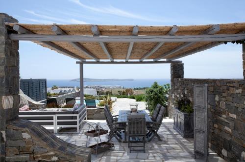 a wooden pergola on a patio with a table and chairs at Alfa Luxury Villas in Chrissi Akti
