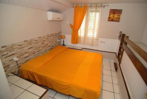 a bedroom with a bed with an orange blanket at villa Prunier in Les Anses-dʼArlets