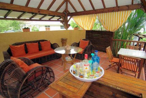 a patio with a couch and a table and chairs at villa Prunier in Les Anses-dʼArlets