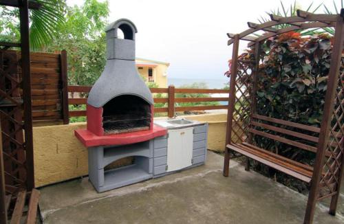 um forno de pizza ao ar livre sentado ao lado de um banco em villa Prunier em Les Anses-dʼArlets