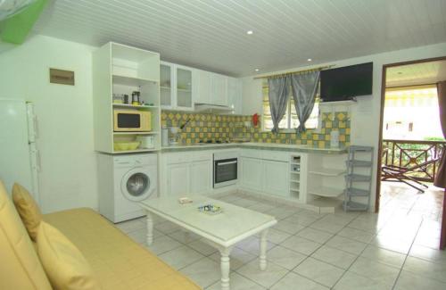 a kitchen with white cabinets and a table in it at villa Prunier in Les Anses-dʼArlets