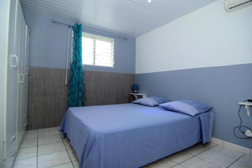 um quarto azul com uma cama e uma janela em villa Prunier em Les Anses-dʼArlets