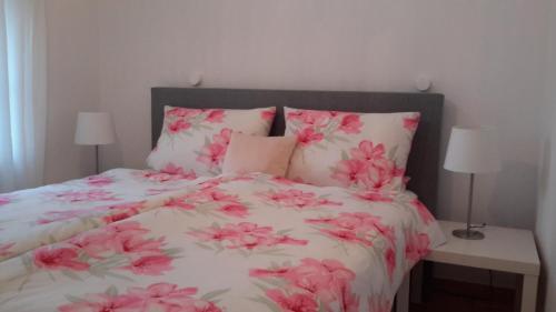 a bed with pink flowers on it with two lamps at An den Tonwerken 24 Ferienwohnung Sunny in Brüggen