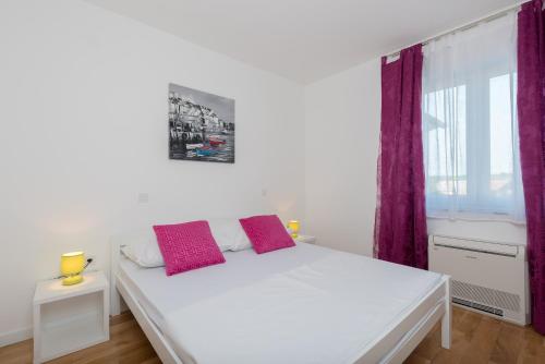 a bedroom with a white bed with two red pillows at Villa Anja 2nd floor in Peroj