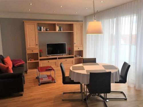 ein Wohnzimmer mit einem Tisch mit Stühlen und einem TV in der Unterkunft ZISA Ferienwohnung Bodensee in Friedrichshafen