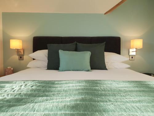 a bed with a green comforter and two lamps at Compston House B & B in Ambleside