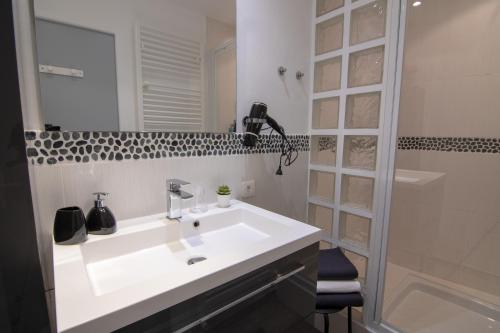 ein Badezimmer mit einem weißen Waschbecken und einer Dusche in der Unterkunft Arles Holiday - La Terrasse in Arles