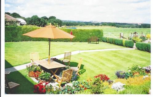a table and chairs with an umbrella in a garden at Ashcroft Farmhouse in East Calder