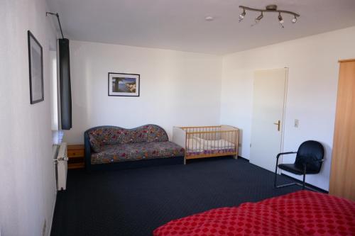 a bedroom with a couch and a crib in a room at Ferienwohnung Hahn in Börgerende-Rethwisch