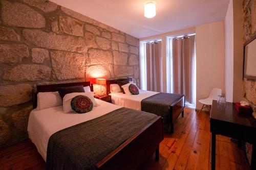 a hotel room with two beds and a stone wall at OportoHouse in Porto