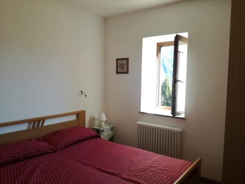 a bedroom with a bed with a red comforter and a window at "La Casina" Relax e Natura a Canal San Bovo in Canale San Bovo