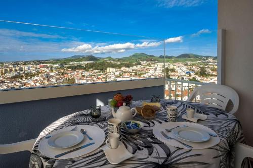 a dining room table with a view of a city at Azores 19th Floor (180º ocean & city view) in Ponta Delgada