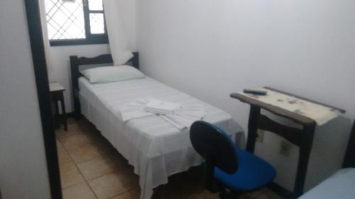 a small bedroom with a bed and a blue chair at Schulz Pousada in Joinville