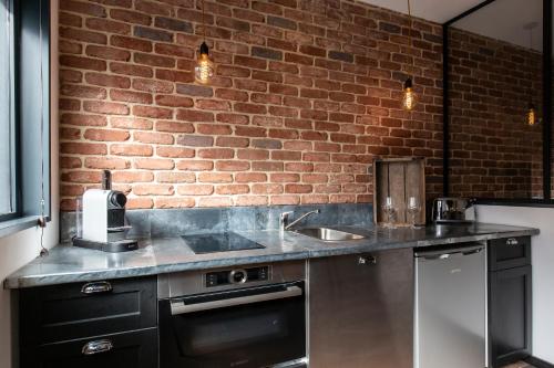 - une cuisine avec un évier et un mur en briques dans l'établissement Suite Vintage Rouen, à Rouen