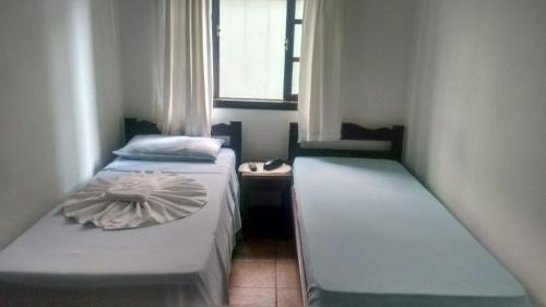 two beds in a small room with a window at Schulz Pousada in Joinville