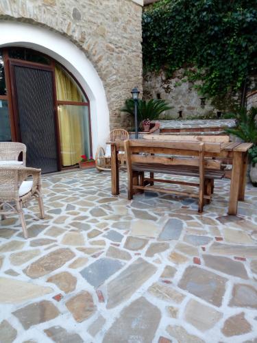 a stone patio with a wooden bench and two chairs at B&B La Carosella in Vatolla