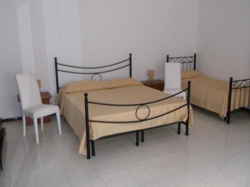 two beds in a bedroom with a chair and a table at centrostoricolipari in Lipari