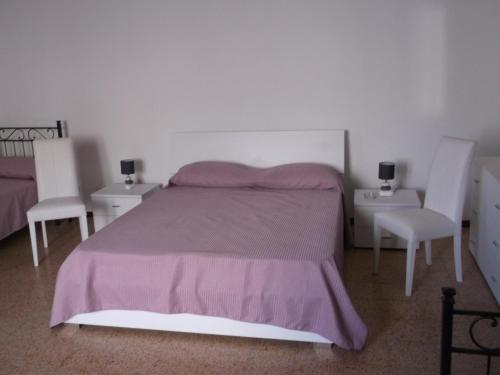 1 dormitorio con 1 cama y 2 sillas blancas en Via Giuseppe Garibaldi 115 en Lipari