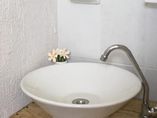 a white sink in a bathroom with flowers in a vase at Maaya in Puerto Morelos