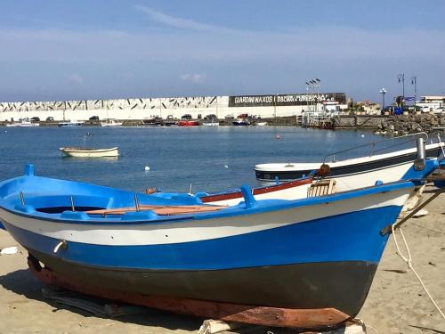 - un bateau bleu et blanc assis sur la plage dans l'établissement Casa Patrizia, à Giardini Naxos