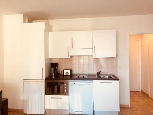 une cuisine avec des armoires blanches et un évier dans l'établissement By the sea, calm studio with terrace, near Monaco, à Beausoleil