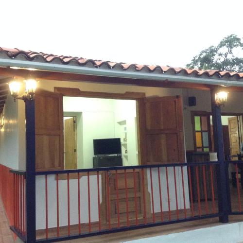 a house with a balcony with a red and white fence at Finca El Sueño De Mi Abuelo in Pereira