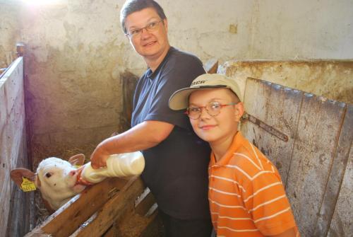 a man standing next to a boy holding a sheep at Bauernhof Familie Tauber-Scheidl in Grossmeinharts