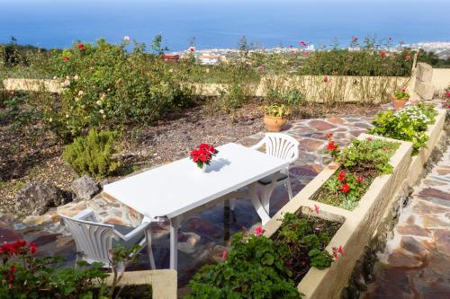 a white table and chairs in a garden with flowers at Casitas La Brenda y La Gaga in Los Realejos