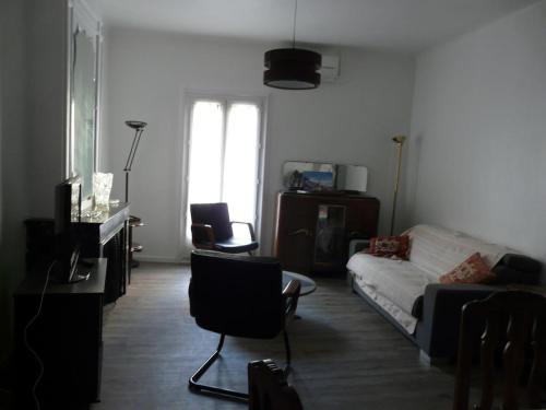 ein Wohnzimmer mit einem weißen Sofa und Stühlen in der Unterkunft T4 de 85m2 avec garage en plein coeur de Sète in Sète