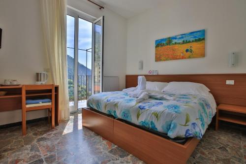 a bedroom with a bed and a desk and a window at La Baia di Rio in Riomaggiore