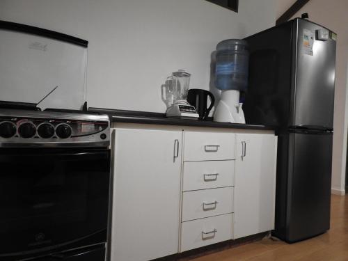 a kitchen with a black refrigerator and white cabinets at Agradable Casa en Condominio Prados del Mar Tongoy RENOVADA in Tongoy