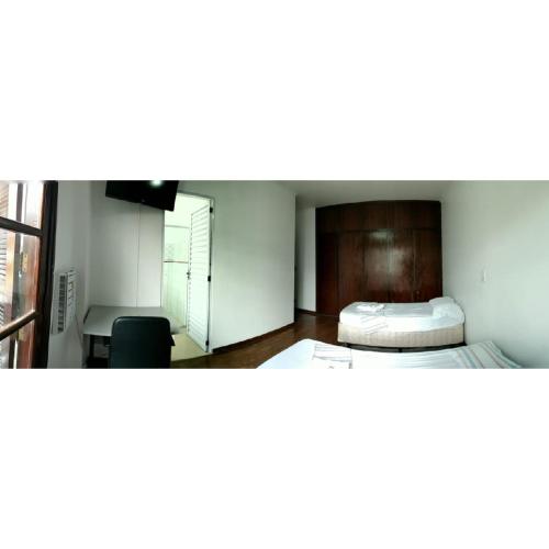 a room with two beds and a desk and a window at Anexo São João in Piracicaba