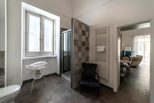 a bathroom with a toilet and a chair in a room at Novecento Dimore di Poesia in Trani