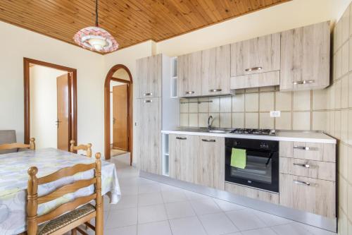 una cocina con armarios de madera y una mesa en una habitación en Residence le Coccinelle vicino a Cefalù, en Campofelice di Roccella