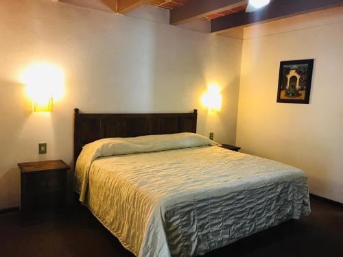 a bedroom with a bed and two lights on the wall at Hotel La Mansión in San José Iturbide