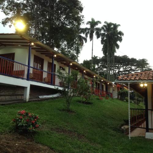 a building with a green yard with a house at Finca El Sueño De Mi Abuelo in Pereira